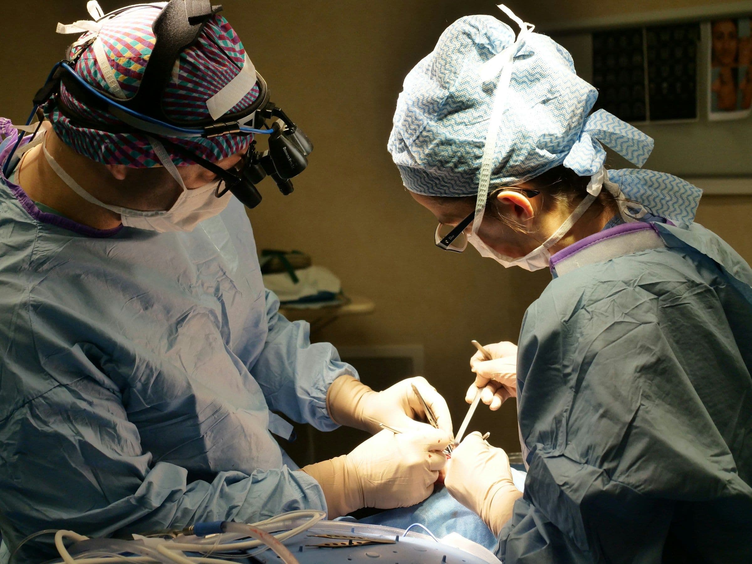 Dos cirujanos con lupas quirúrgicas trabajando en el campo operatorio