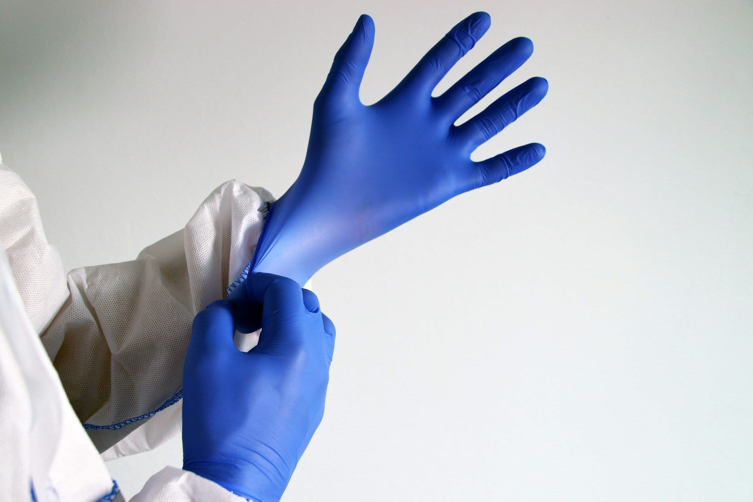 Manos colocándose guantes quirúrgicos azules antes de un procedimiento